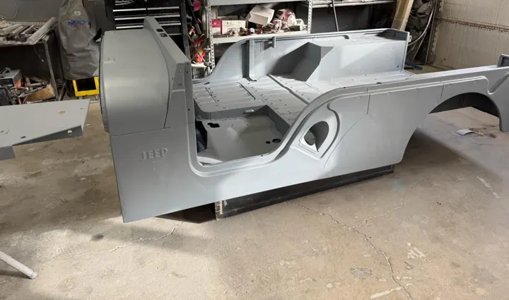 Jeep CJ body tub in primer on a rotisserie in the paint booth